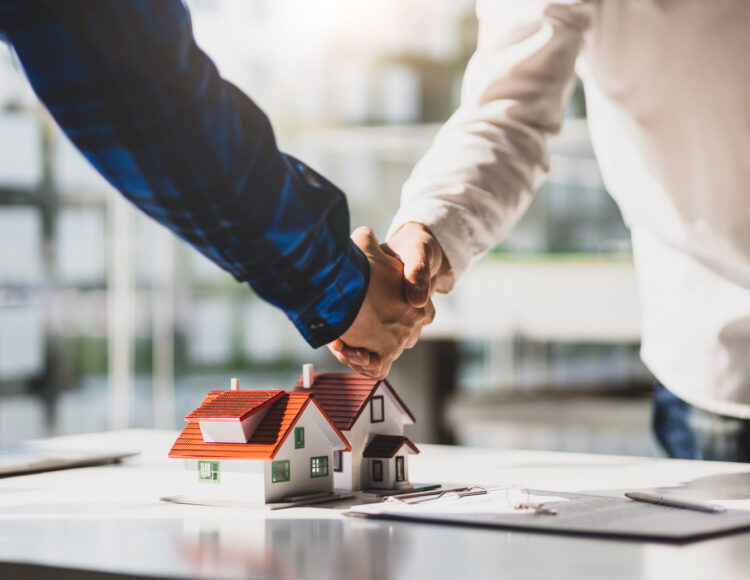 Real estate agents shake hands after the signing of the contract agreement is complete.